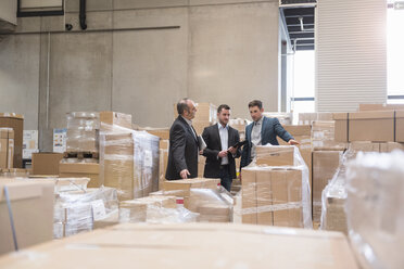 Three men in factory warehouse surrounded by cardboard boxes - DIGF01742