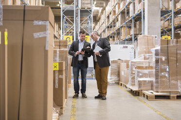 Two men talking in factory warehouse - DIGF01746