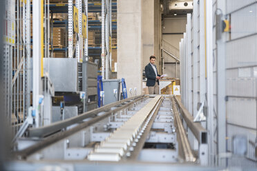 Businessman at conveyor belt in factory - DIGF01750