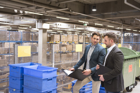 Two businessmen with documents talking in factory warehouse - DIGF01754