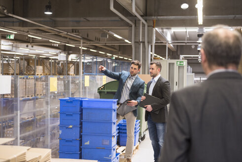 Three businessmen in factory warehouse - DIGF01755