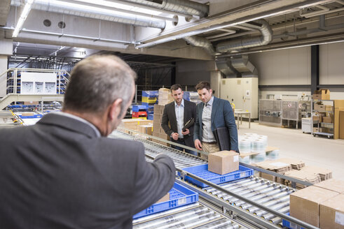 Three businessmen at conveyor belt in factory - DIGF01759