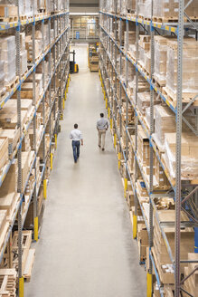 Two men walking in factory warehouse - DIGF01777