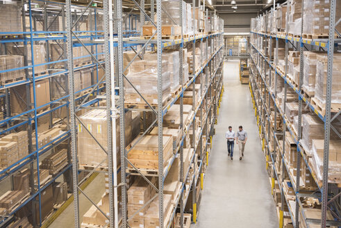 Two men walking in factory warehouse - DIGF01779