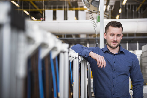 Porträt eines selbstbewussten Geschäftsmannes in einer Fabrikhalle - DIGF01840