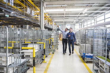 Two men walking and talking in factory shop floor - DIGF01848