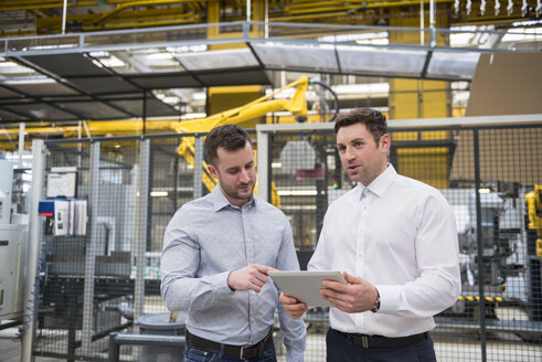 Two men with tablet talking in factory shop floor - DIGF01858