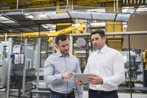 Zwei Männer mit Tablet im Gespräch in einer Fabrikhalle - DIGF01858