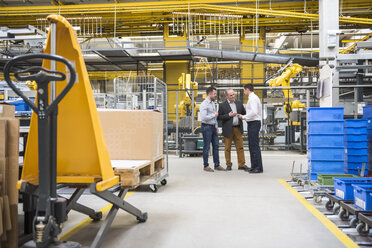 Three men talking in factory shop floor - DIGF01863