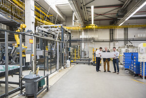 Three men with blueprint talking in factory shop floor - DIGF01867