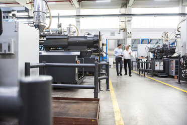 Two men with tablet talking in factory shop floor - DIGF01886