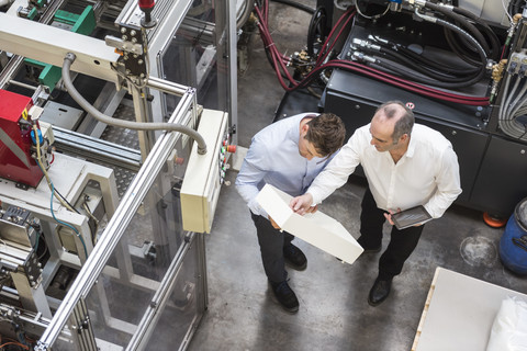 Top view of two men in factory shop floor talking about product stock photo