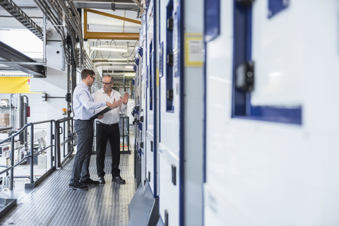 Two men talking in factory shop floor stock photo