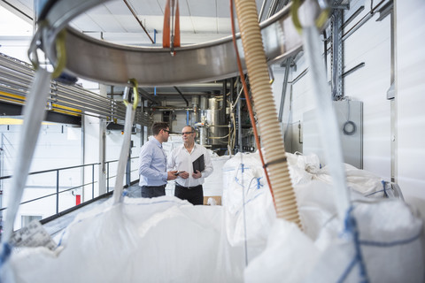 Two men talking about materials in factory stock photo