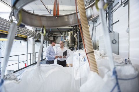 Zwei Männer sprechen über Materialien in einer Fabrik, lizenzfreies Stockfoto