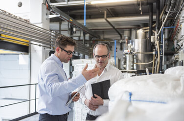 Two men talking about materials in factory - DIGF01917