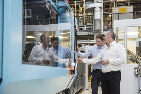 Two men looking at machine in factory shop floor - DIGF01946