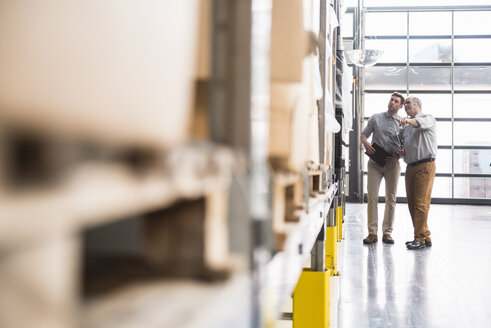 Two men talking in factory warehouse - DIGF01963