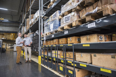 Two men standing in factory warehouse - DIGF01965