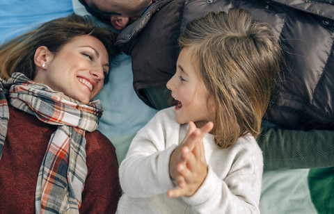 Glückliches Mädchen mit ihrer Familie auf einer Decke und klatschenden Händen, lizenzfreies Stockfoto