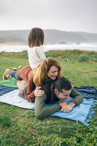 Glückliche Familie auf einer Decke an der Küste, lizenzfreies Stockfoto