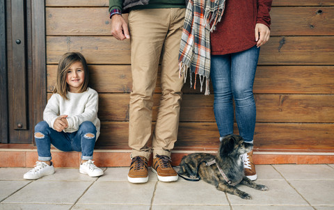 Smiling girl with parents and dog at wooden wall stock photo