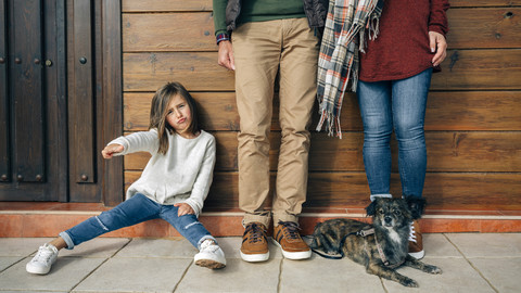 Mädchen mit Eltern und Hund an Holzwand gestikulierend, lizenzfreies Stockfoto