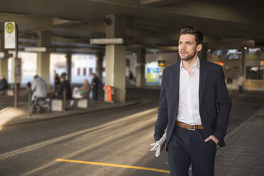 Porträt eines jungen Geschäftsmannes, der am Busbahnhof wartet - DIGF02002