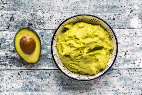 Bowl of avocado hummus and half of avocado stock photo