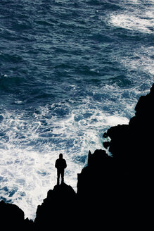 Portugal, Madeira, silhouette of man at rocky coast by the sea - DWIF00849