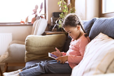 Kleines Mädchen benutzt sitzendes Tablet, sitzend auf Couch - HAPF01486