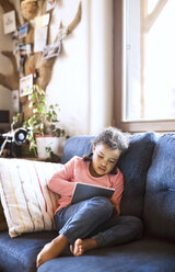 Little girl using sitting tablet, sitting on couch - HAPF01489