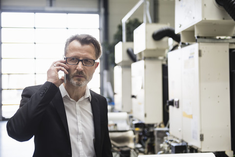 Businessman in factory shop floor on the phone stock photo