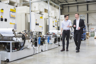 Two men walking and talking in factory shop floor - DIGF02022