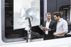 Zwei Männer in einer modernen Fabrik sprechen über ein Produkt - DIGF02026