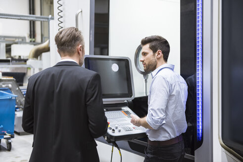 Two men talking at control in modern factory - DIGF02028