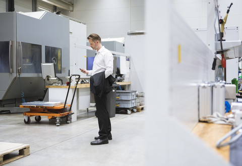 Businessman in factory shop floor looking on the phone stock photo