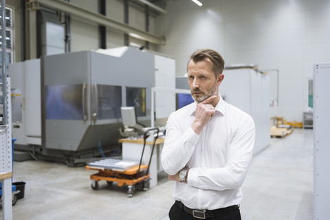 Pensive businessman in factory shop floor stock photo