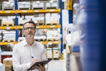 Man in storehouse taking notes - DIGF02038