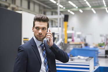 Businessman in factory shop floor on the phone - DIGF02042