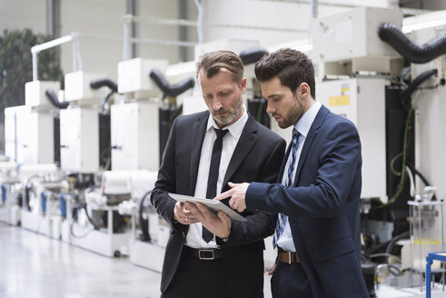 Two businessmen sharing tablet in factory shop floor - DIGF02048