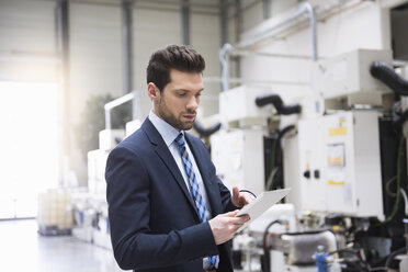 Businessman in factory shop floor using tablet - DIGF02050