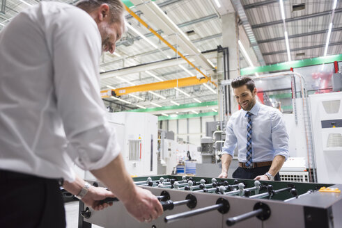 Zwei Kollegen spielen Tischfußball in einer Fabrik - DIGF02062