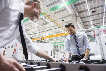 Two colleagues playing foosball in factory - DIGF02063