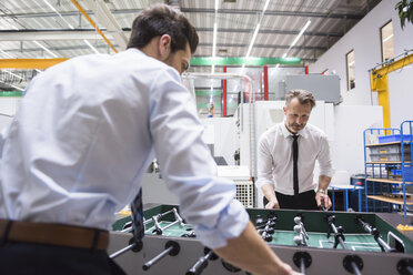 Zwei Kollegen spielen Tischfußball in einer Fabrik - DIGF02064