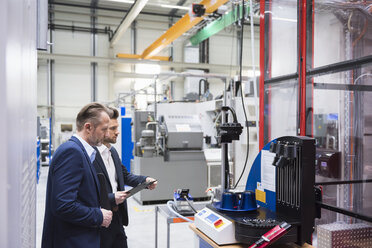 Two businessmen in factory shop floor examining machine - DIGF02066