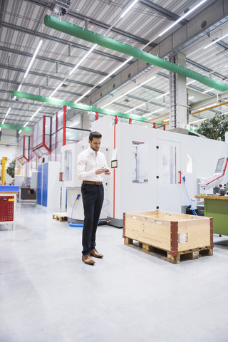 Mann in Fabrikhalle mit Produkt in der Hand, lizenzfreies Stockfoto