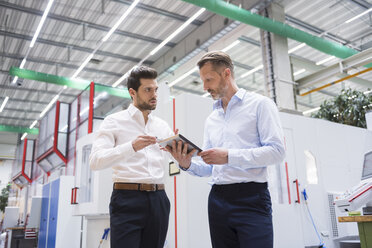 Two businessmen with tablet in factory shop floor discussing - DIGF02076