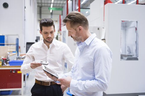 Zwei Männer mit Tablet und Produkt in einer Fabrikhalle - DIGF02078