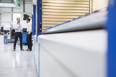 Two businessmen standing in factory shop floor - DIGF02084